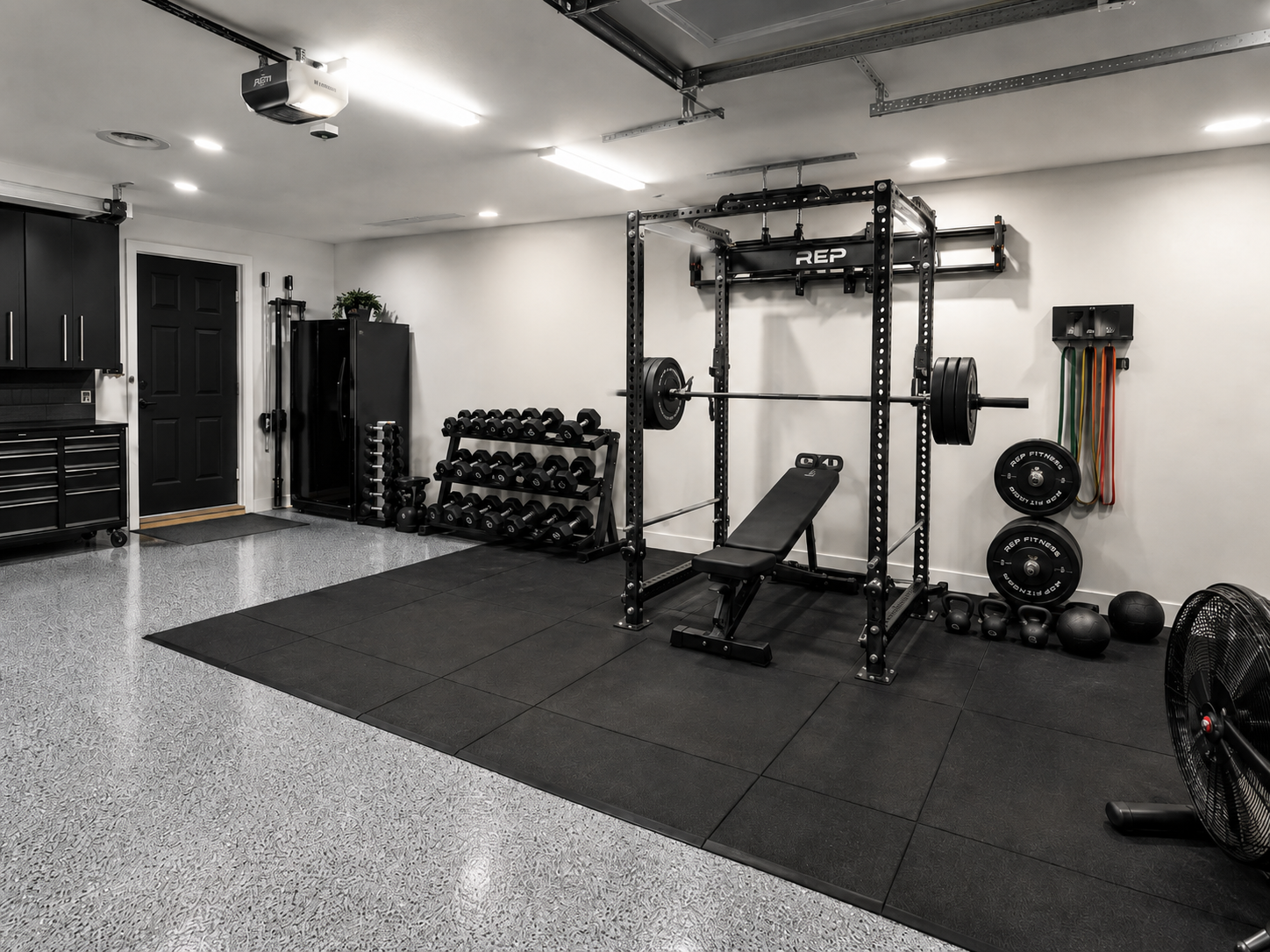 Finished garage gym with rubber flooring, power rack, and mirror wall